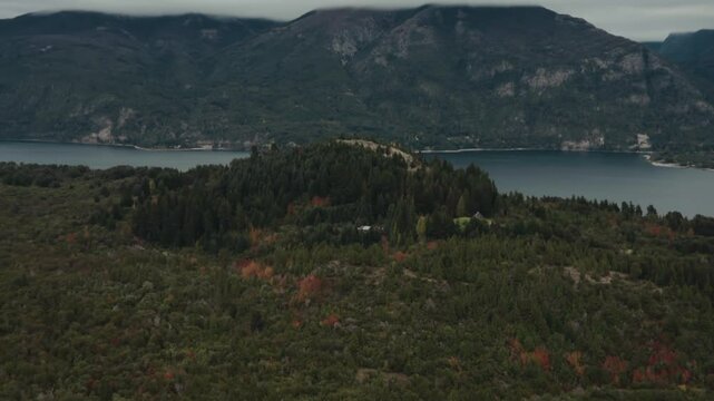 Zoom in to cottage in the middle of forest with lake in background. Bariloche Argentina. Moreno Lake