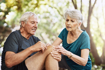 Outdoor, old couple and knee pain with bruise, exercise or ache with inflammation, medical condition or support. Accident, broken or senior man with mature woman, muscle tension or runner with injury
