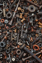 A dense collection of nuts, bolts, and screws, tightly packed to fill the entire frame. The hardware comes in various sizes and metallic finishes, creating an industrial and detailed background. 