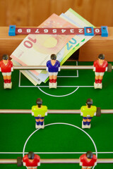Money lying on foosball game, vertical shot, sports betting, victory in competition, sports table football game