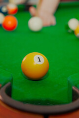 ball with number one in front of the hole on the billiard table, playing billiards, preparation for a shot in billiards, playing eight on billiards