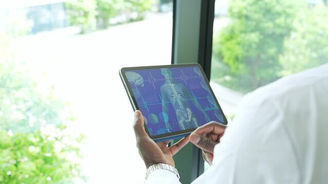 Group of medical workers or researchers in white coats looking at medical data on a tablet