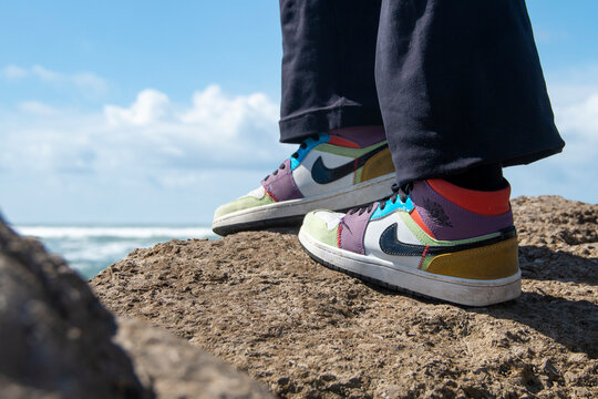Nike Jordan sports shoes, worn by a woman standing on a rock with the sea in the background