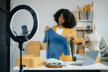 Beautiful lady blogger showing clothes in front of the camera to recording vlog video live...