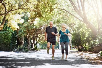 Running, outdoor and old couple with sunshine, exercise and bonding together with retirement. Park, senior man and mature woman with training, challenge and hobby with fitness, summer and wellness
