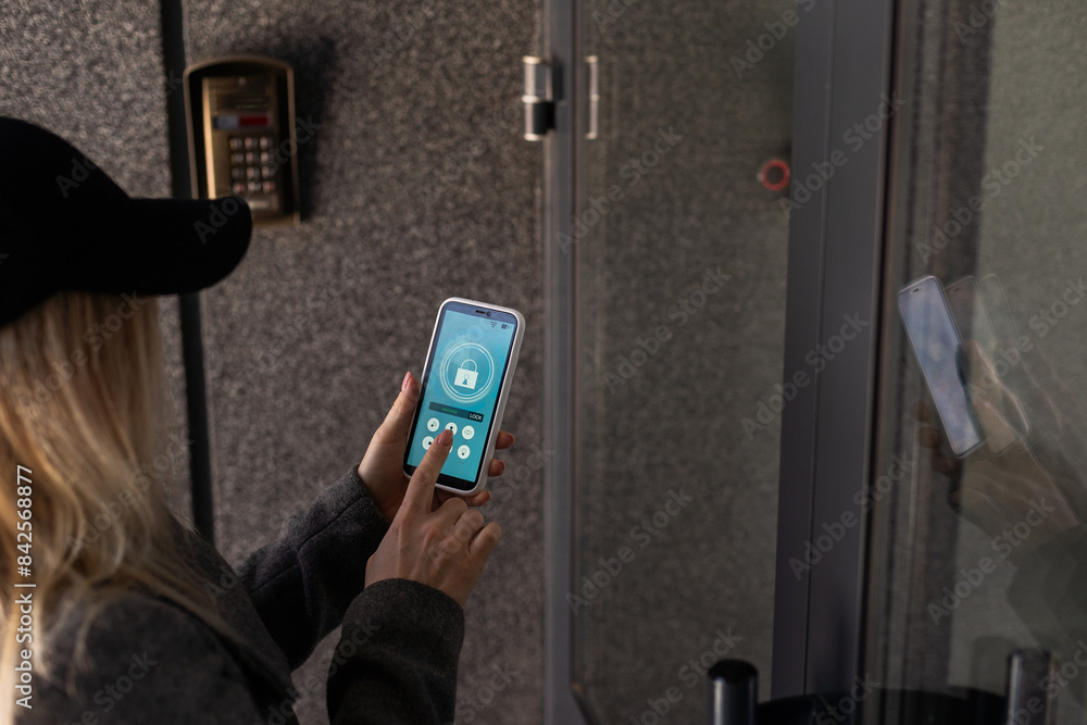 Poster woman locking smartlock on the entrance door using a smart phone. concept of using smart electronic 