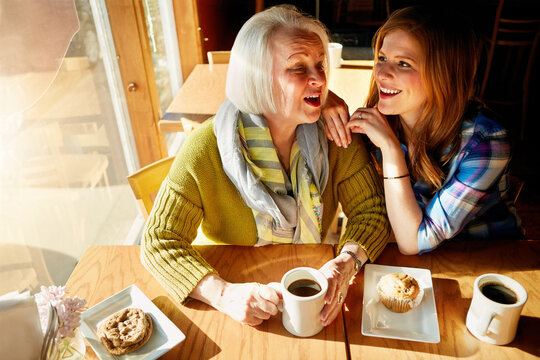 Senior woman, joke and daughter happy in cafe for memories or bonding to relax. Restaurant, coffee shop and discussion with people, conversation and family smiling with love and muffin in France. - Powered by Adobe