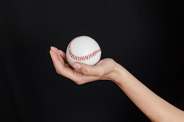 Hand holding a baseball on black background. Baseball game concept