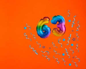 Multicolor balloon number 63 - Confetti explosion on orange background. Birthday card