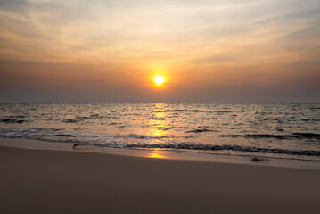 Obraz premium The sun is setting over the ocean, casting a warm glow on the water. Pantai Kartini beach