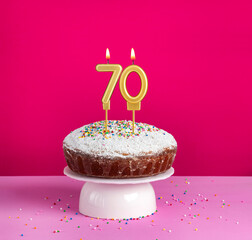 Birthday cake with number 70 candle on pink background