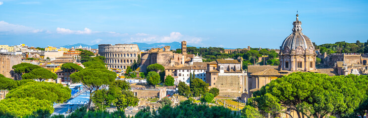 Obraz premium A panoramic view of the Roman Forum and Colosseum in Rome, Italy. The iconic amphitheater stands prominently in the distance, while ancient ruins and modern buildings fill the foreground.