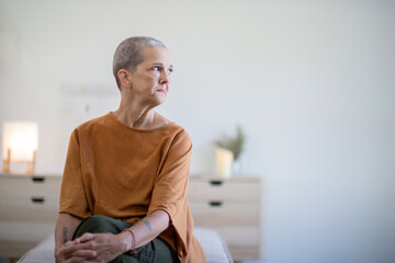 Elderly woman sitting at home, deep in thought. Concept of aging and reflection