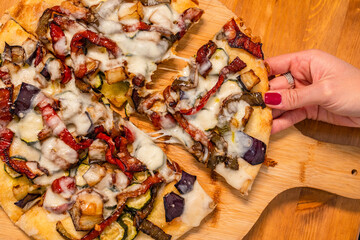 Pizza rotonda cotta in forno nel ruoto condita con melanzane, peperoni, zucchine e mozzarella...