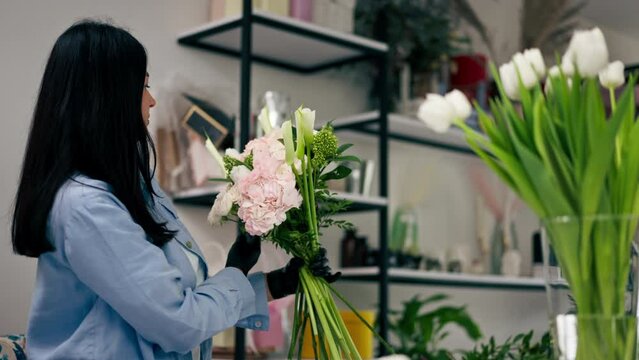 flower shop girl near white table collects a flower arrangement of a beautiful bouquet of white flowers