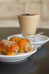 Crema di caffè fredda guarnita con cacao e chicchi di caffè e due dolci ripieni di crema al pistacchio serviti come colazione servita in un bar elegante