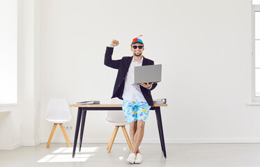 Funny happy business man standing on workplace in office wearing beach shorts and suit jacket...