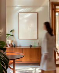 70 x 100cm, 28 x 39 inch, wood frame mockup in a kitchen dining room with modern mid century furniture, with a blurry person woman walking by © Amy