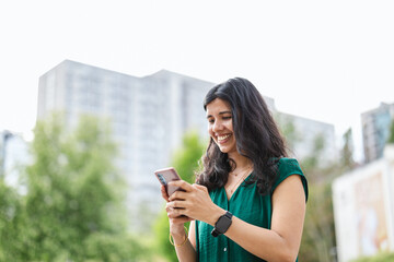 Smiling young woman using her smartphone in the city
