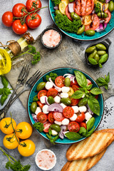 Colorful salad in a bowl: tomatoes, mozzarella cheese, basil and olives. Top view.