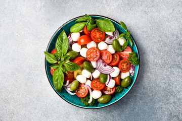 Traditional Italian salad: tomatoes, mozzarella cheese, basil and olives. Caprese. On a gray...