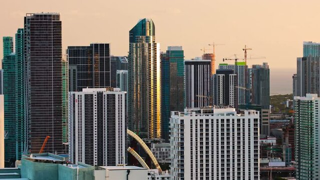 4k The urban skyline of business downtown Miami at sunset. Featuring modern skyscrapers and bustling construction, reflects the city sophistication and vibrant life, illuminated by the setting sun.