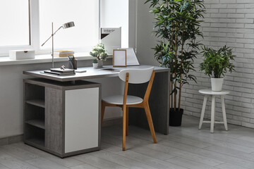 Stylish workplace with tablet computer and desk lamp in interior of modern office
