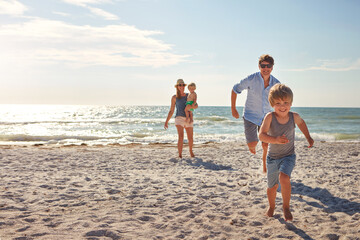 Happy, family and children playing on the beach on holiday, travel or adventure in summer. Boy, father and kids with parents and outdoor ocean for fun energy and happiness with a game while running