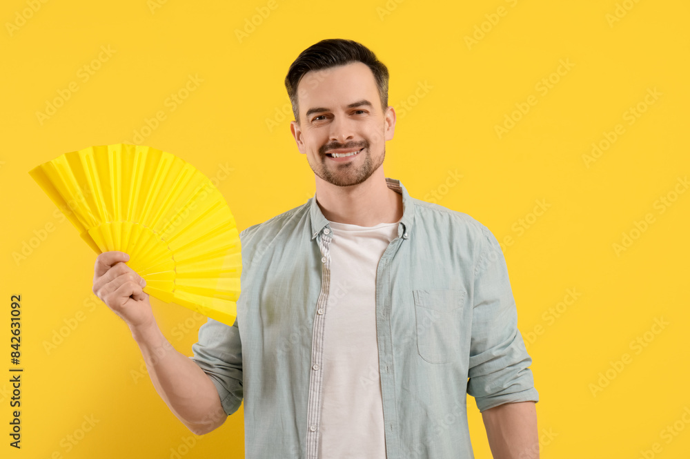 Sticker Young man with fan on yellow background