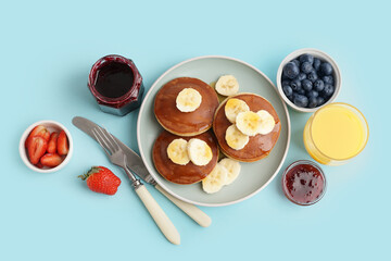 Tasty pancakes with honey and banana on blue background