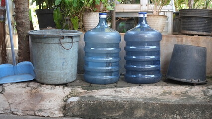 Obraz premium Plastic waste items, recycled items, empty water gallons, plastic and paper buckets to save the environment. Green tree background. Environmental saving concept.