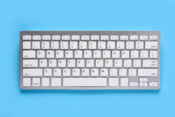 Grey computer keyboard on blue background. Top view