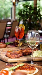 A festive table in a restaurant on a summer terrace with alcoholic drinks and meat and pork food