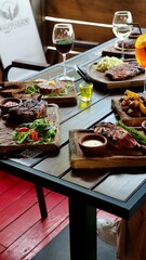 Food in a restaurant with meat pork, steak, sausages, tartar on a table with drinks on a summer terrace