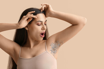 Beautiful young shocked woman with confetti on her armpit against beige background. Depilation concept