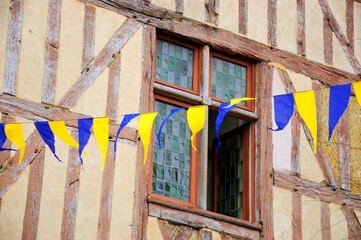 Street decorated with yellow blue flags garland for medieval festival. Ancient half timbered house at background. Provins, France. 