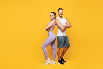 Full body young confident cool strong fitness trainer sporty two man woman wear blue clothes spend time in home gym stand back to back isolated on plain yellow background. Workout sport fit concept.