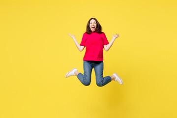 Full body young surprised shocked woman wear pink t-shirt casual clothes jump high with...