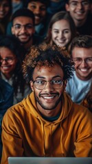 Obraz premium A young, curly-haired man in a yellow hoodie smiles at the camera with a diverse group of friends around a laptop