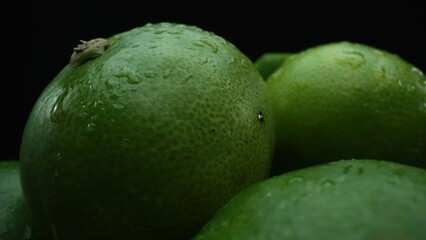 Slices of lime are meticulously arranged in a pile, set against a black background. Each lime slice is captured in stunning detail, its vibrant green hue and enticing texture. Close up. Comestible.