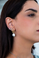 Young woman wearing pearl earrings and stud earrings with zirconia.