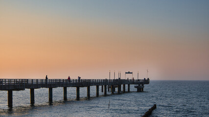 Fototapeta premium Perspektivischer Blick entlang der hölzernen Seebrücke von Heiligendamm mit modernen Laternen und Sitzbänken zur blauen Stunde, maritimes Wahrzeichen, Mecklenburg-Vorpommern, Deutschland
