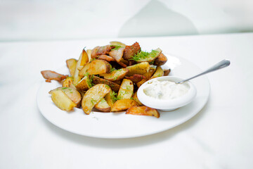 A plate of potatoes with a white sauce and a spoon