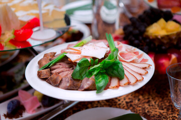 A plate of food with a variety of meats and vegetables. The plate is on a table with other food items