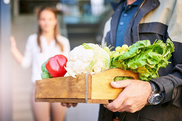 Delivery man, closeup and box of vegetables groceries at front door as courier service for...