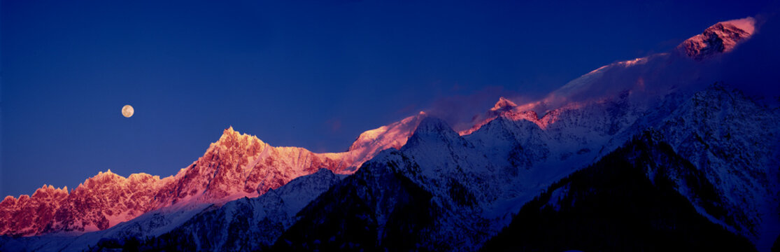 View of snowy mountains at sunset with moonrise, Chamonix-Mont-Blanc, France.