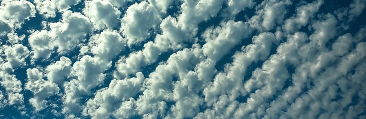 A mesmerizing image of patterned clouds that appear like waves against a clear blue sky, creating a unique and artistic representation of nature's beauty and symmetry.