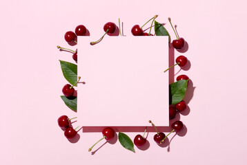 Square pink frame and ripe cherries on a pink background. Cherries or sweet cherries on a pink background. Top view. Space for text.