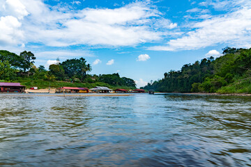 a river with a boat and a forest on the side of it with floating restaurant of Taman Negara