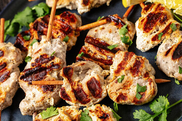 grilled mini pork skewers on a plate, top view